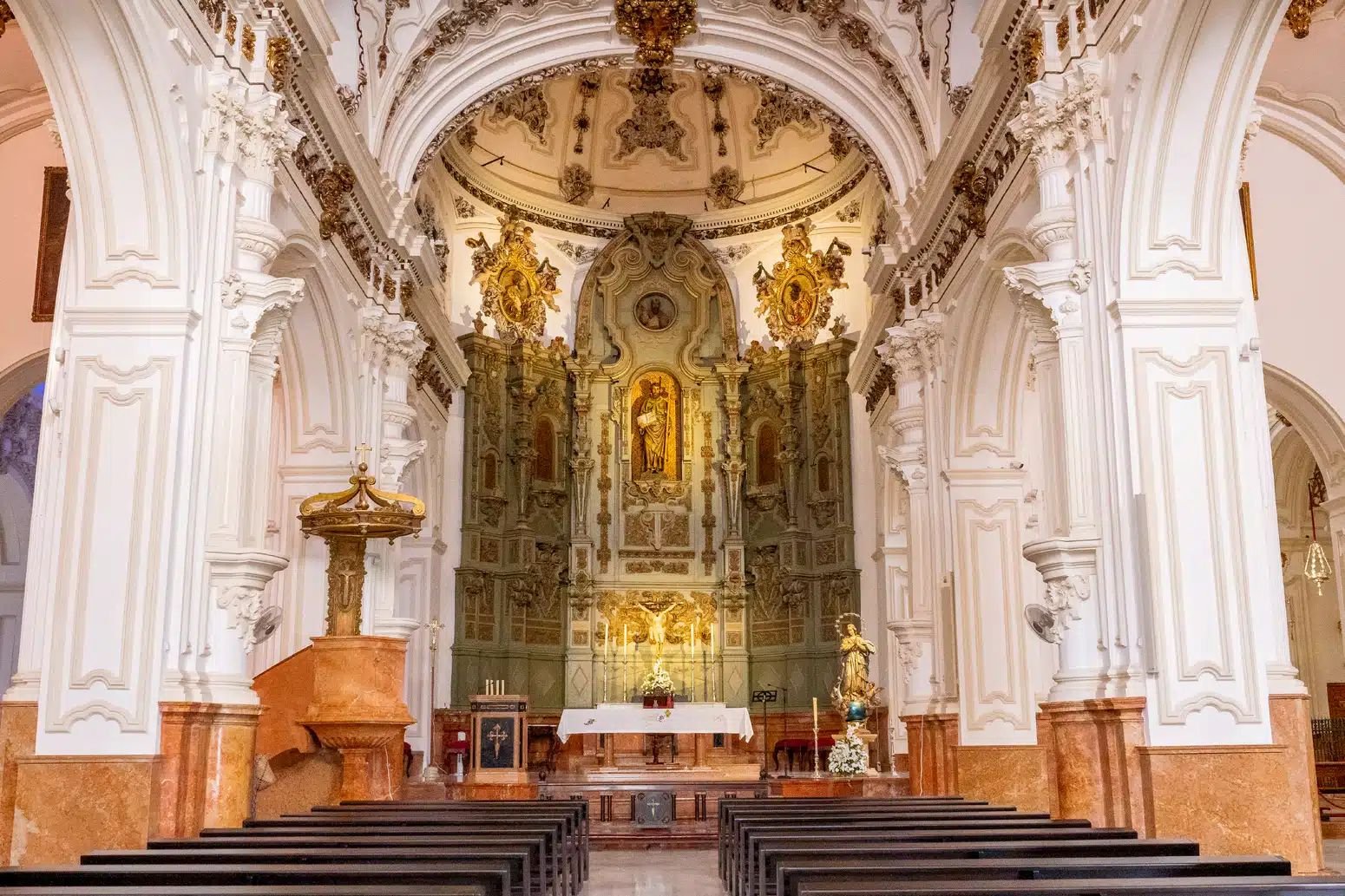 Interior of Iglesia de Santiago Apóstol in Málaga with ornate altar and baroque details
