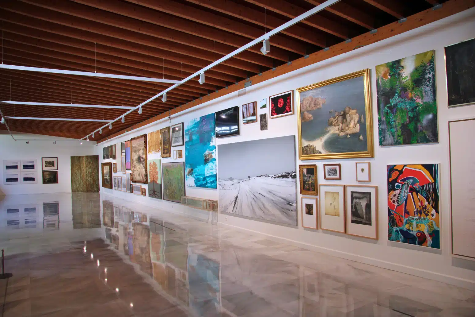 Interior view of MuCAC Málaga La Coracha with contemporary paintings displayed on a white wall