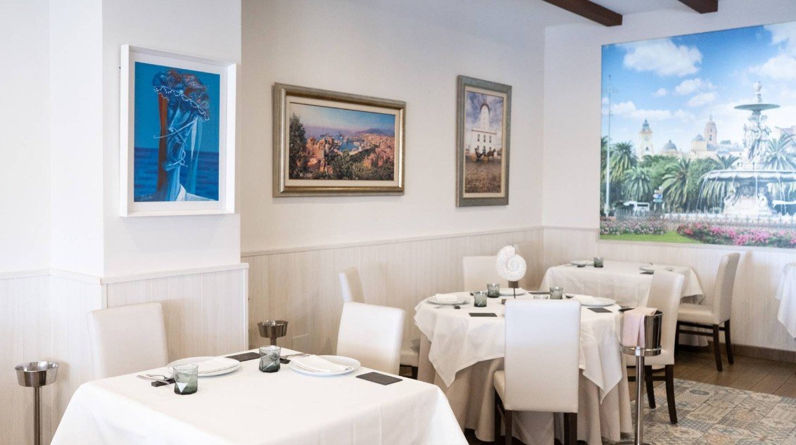 Elegant interior of Hermanos Alba seafood restaurant in Malaga, with white tablecloths and local artwork on the walls